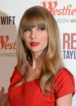 Taylor Swift 在 Westfield London 活動中穿著紅色連衣裙，搭配大膽的紅色唇膏。
