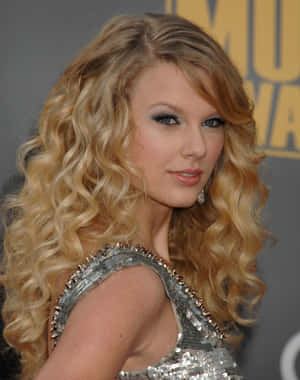 Taylor Swift 在音樂頒獎典禮上穿著銀色亮片連衣裙，金色捲髮。