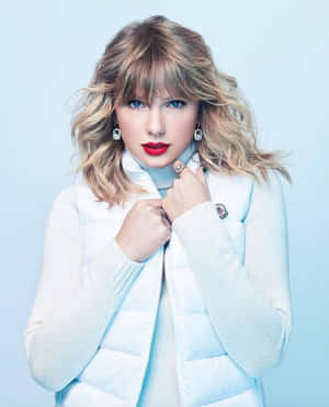 Taylor Swift 身穿淺藍色羽絨背心，塗紅色唇膏，金髮。
