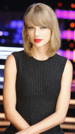 Taylor Swift 身穿黑色連衣裙，紅唇，在燈光舞台上