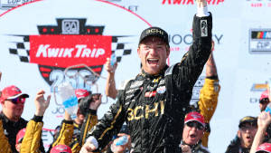 NASCAR車手在贏得比賽後在頒獎台上噴灑香檳，粉絲們歡呼慶祝。