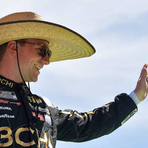 戴草帽和太陽眼鏡的NASCAR車手向人群揮手。
