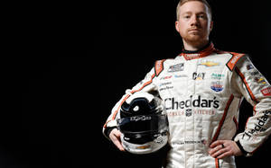 NASCAR車手身穿賽車服在黑色背景下拿著頭盔