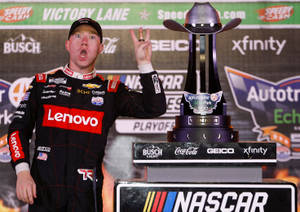 NASCAR車手在帶有牛仔帽的獎盃旁以和平手勢慶祝勝利。
