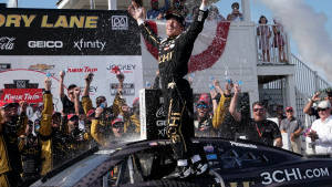 NASCAR車手在賽車上慶祝勝利，香檳噴灑，人群歡呼。