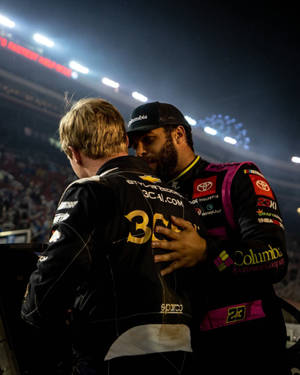 兩位NASCAR車手在體育場燈光下賽後擁抱，伴隨煙花。