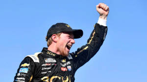 NASCAR車手在晴朗的藍天下高舉拳頭慶祝勝利。