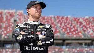 NASCAR車手身穿賽車服在日落時分的體育場中自信站立。