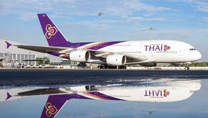 泰國航空空中巴士A380飛機在機場濕滑停機坪上的倒影。