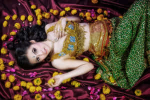 穿著傳統印度服飾的女性躺在栗色綢緞上，周圍有萬壽菊和玫瑰花瓣。