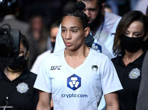 身穿白色球衣的女性UFC拳手在體育賽事中經過保安人員。