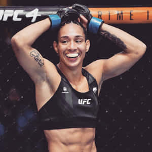 女性MMA拳手在八角籠內微笑舉起雙臂。