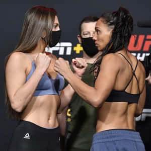 兩名穿著運動服的女性拳手在賽前對峙中鎖定拳頭。
