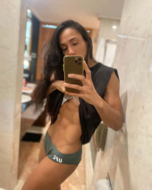 一位身材健美的女性在酒店浴室穿著綠色內衣和黑色上衣對著鏡子自拍。 — 健身 壁紙