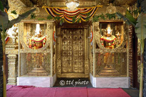 金色寺廟門口，有神像和花卉裝飾。