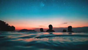 四個人在星空暮色天空下的水中剪影。