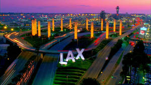 暮色中的 LAX 機場，閃爍的柱子和車輛光跡。