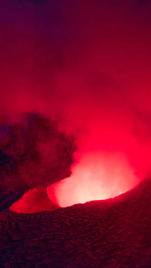 一個發光的紅色火山口，帶有熔岩和煙霧。