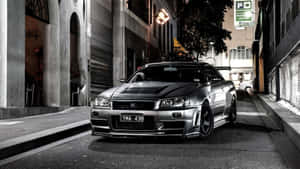 銀色日產Skyline R34在夜間停放在狹窄的城市小巷中。