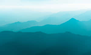 寧靜的山景，層疊的山峰在藍色薄霧中逐漸消失。 — 青綠色 GIF 壁紙