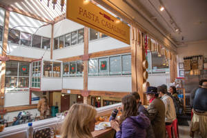 人們在繁忙的意粉餐廳用餐，餐廳有木樑和掛牌。