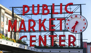 Public Market Center 的紅色標誌，帶有一個大時鐘，在藍天下顯示 7:35。