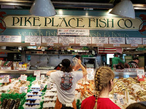 顧客和員工在 Pike Place Fish Co. 處理冰上的新鮮海鮮。