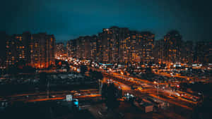 夜晚的城市，燈火通明的建築物和道路上移動的汽車。 — 夜晚 GIF 壁紙