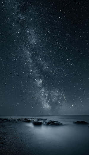 夜間海洋上空的銀河系，伴有流星和岩石海岸。 — 夢境 GIF 壁紙
