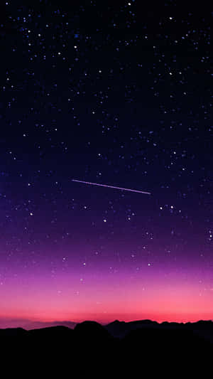 一顆流星劃過黑暗山脈輪廓上方的星空暮色天空。 — 雲朵 壁紙