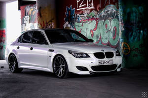 白色BMW M5停放在佈滿塗鴉的城市高架橋下。