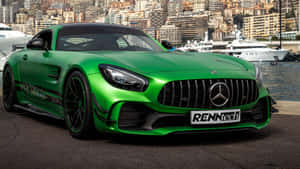 綠色RENNtech Mercedes AMG GT停泊在遊艇碼頭，旁邊有遊艇和城市建築。 — 平治 AMG 壁紙