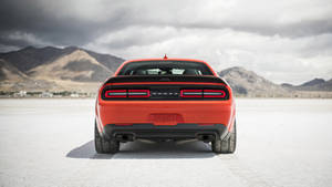 橙色道奇挑戰者在鹽灘上，背景有山脈。 — Dodge challenger GIF 壁紙