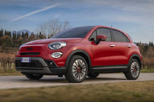 紅色Fiat 500X SUV在鄉村道路上行駛，背景有山脈。