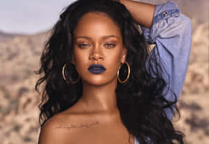 Rihanna 在沙漠中穿著牛仔褲和金色耳環，塗著藍色唇膏。