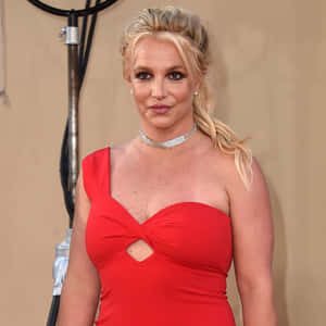 Britney Spears 在正式活動中穿著紅色連衣裙和鑽石頸鏈。