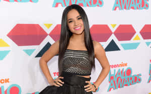 年輕女性穿著黑色禮服在TeenNick Halo Awards紅地毯上微笑。