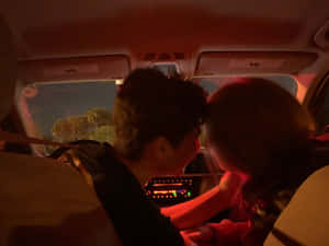兩人在夜晚的車內，紅色燈光下緊靠而坐。