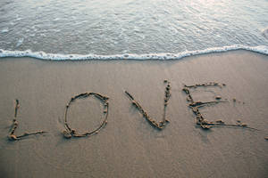 海浪逼近時，沙灘上寫著love這個詞。 — 愛心 壁紙