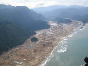 山脈與泥濘河口和帶有波浪的碧綠海水交匯的鳥瞰圖。