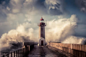 燈塔在暴風雨的海岸場景中承受著洶湧的海浪。 — 燈塔 壁紙