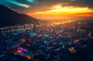 日落時的城市景觀，發光的建築物和河流倒映著金色的天空。 — 建築 壁紙