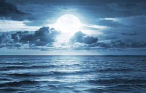 滿月在多雲的夜空下照耀著平靜的海洋。