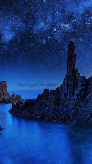 繁星點點的夜空，岩石懸崖和平靜的水面反射星星 — 藍色美學 壁紙