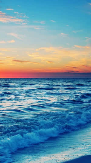 夕陽下，海浪拍打海岸，天空呈現鮮豔的橙色和藍色。