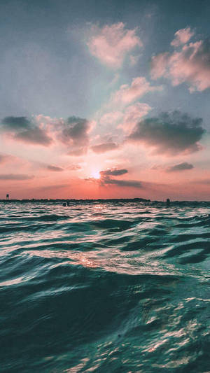 夕陽下的海洋，粉橙色天空和藍綠色海浪 — 沙灘 壁紙