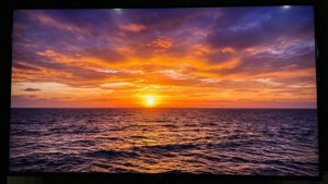 海洋上充滿活力的夕陽，橙色和紫色的雲彩倒映在水面上