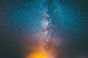 銀河系在繁星點點的夜空中散發著青綠色和橙色的色調。