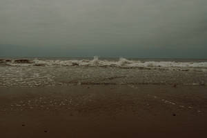 在灰色的暴風雨天空下，海浪拍打著沙灘。 — 海浪 壁紙
