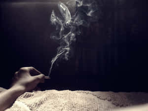 在黑暗背景下，手拿著點燃的香煙，煙霧升起。 — 煙霧動畫 壁紙